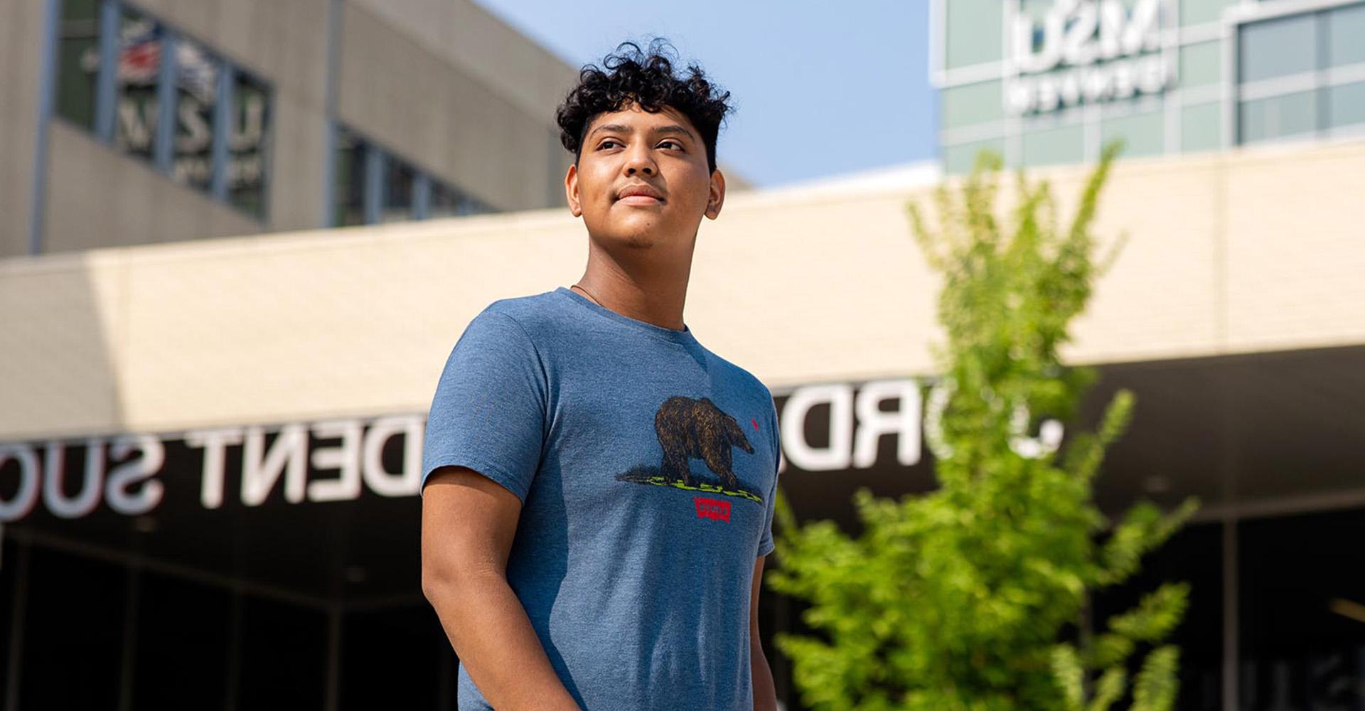 Student Luis Hernandez stands in front of the Jordan Student Success Building.